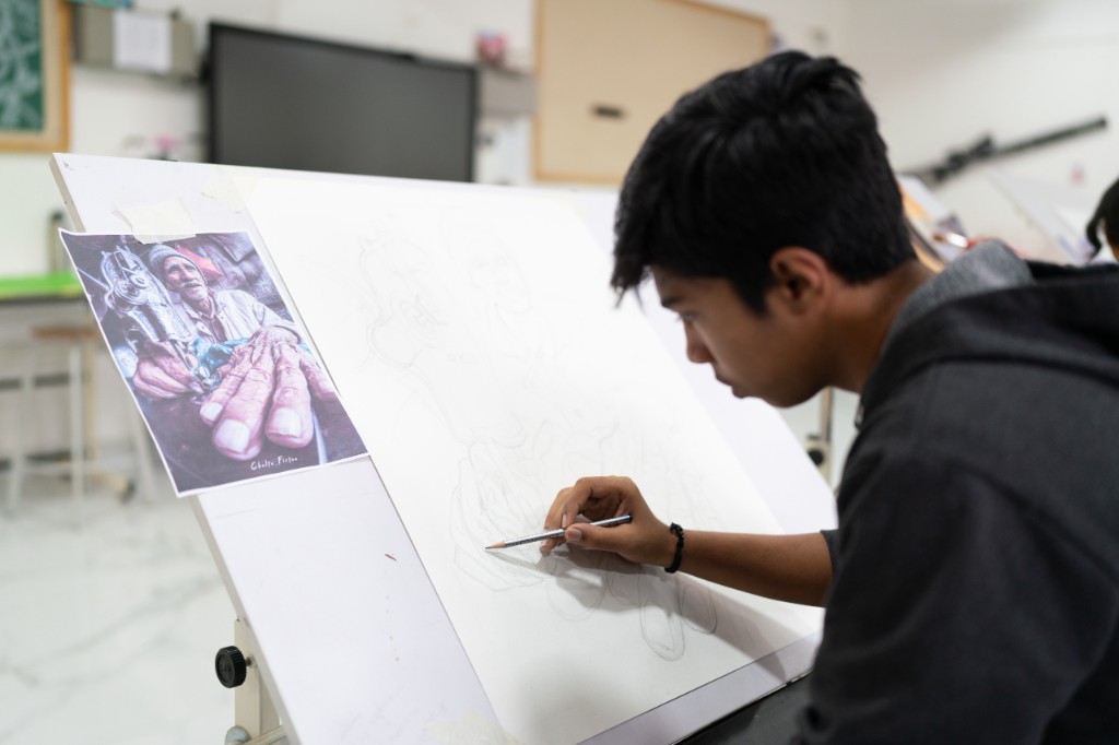 Student sketching a portrait in the art studio at TACS