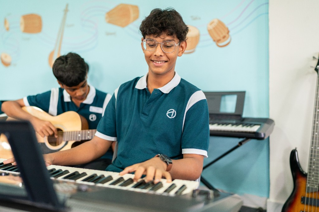 Students learning keyboard and guitar in music class at TACS